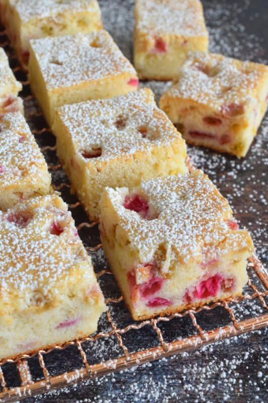 the three ingredient rhubarb squares are sitting on a cooling rack with powdered sugar