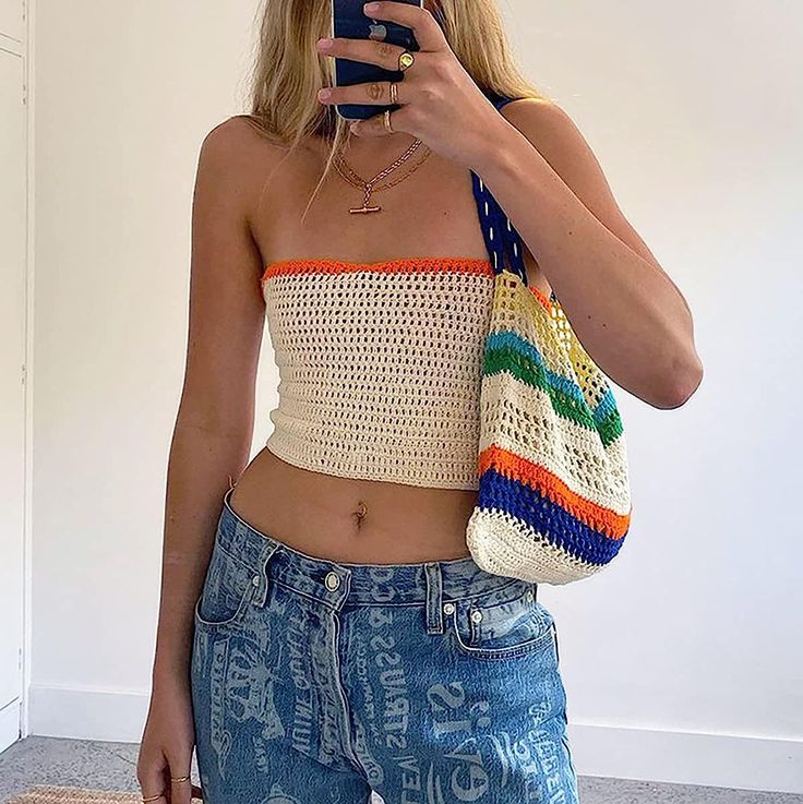 a woman taking a selfie while holding a cell phone in her right hand and wearing a crochet top