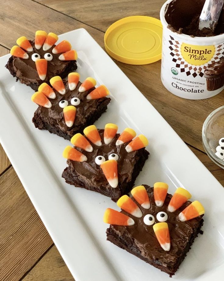 three brownies decorated like turkeys on a white plate with chocolate frosting and candy