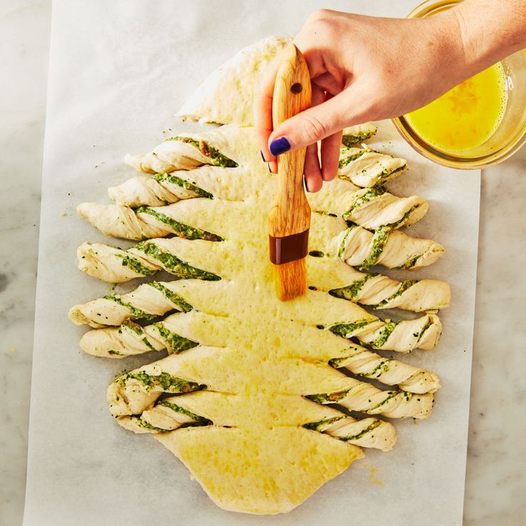 a person is spreading sauce on top of chicken wings with a wooden spatula and a glass of orange juice