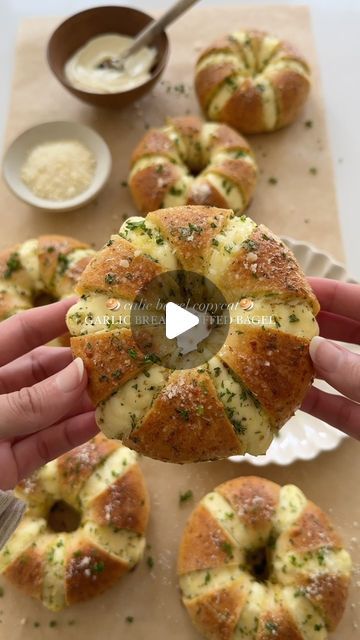 someone is holding a piece of bread in front of other buns on a cutting board