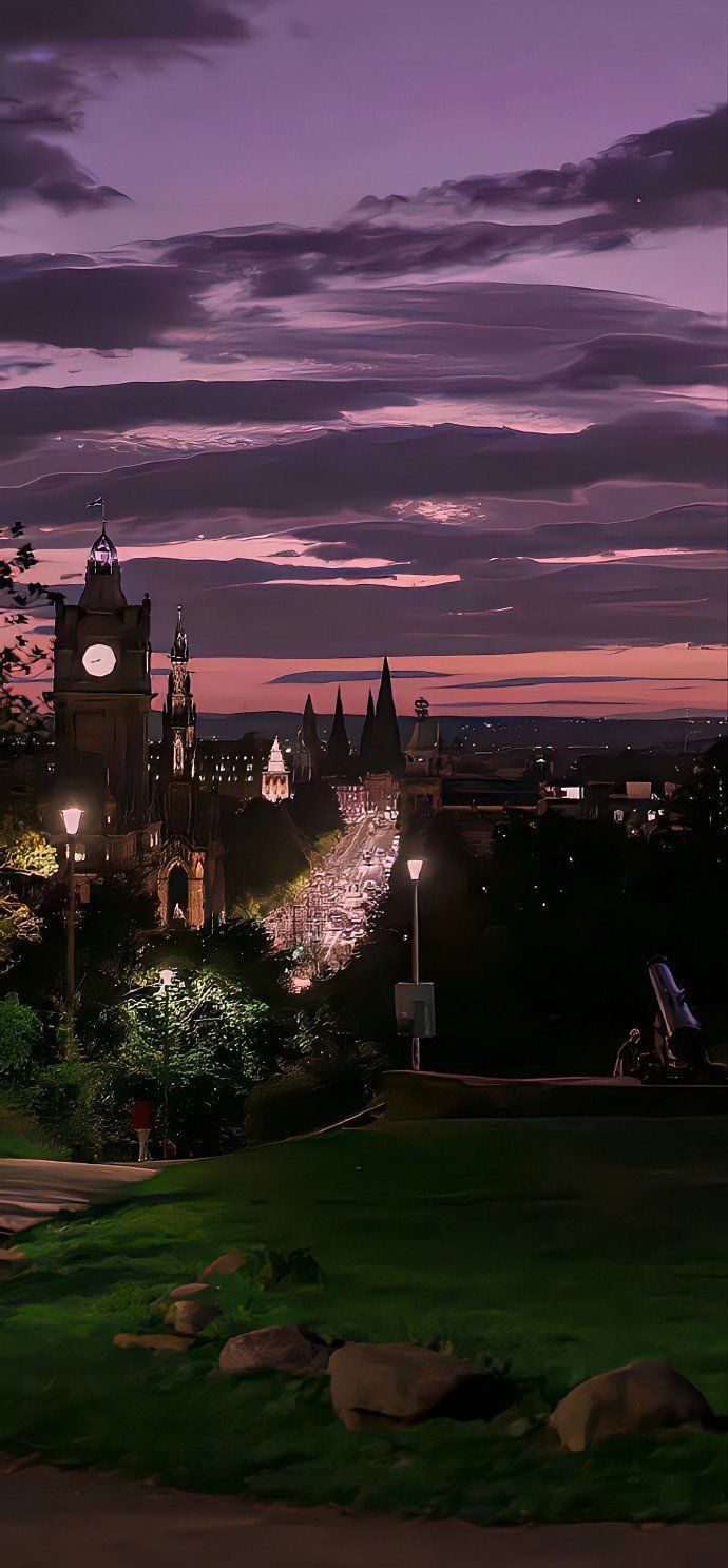 the city lights shine brightly at night as seen from an overlook point on top of a hill