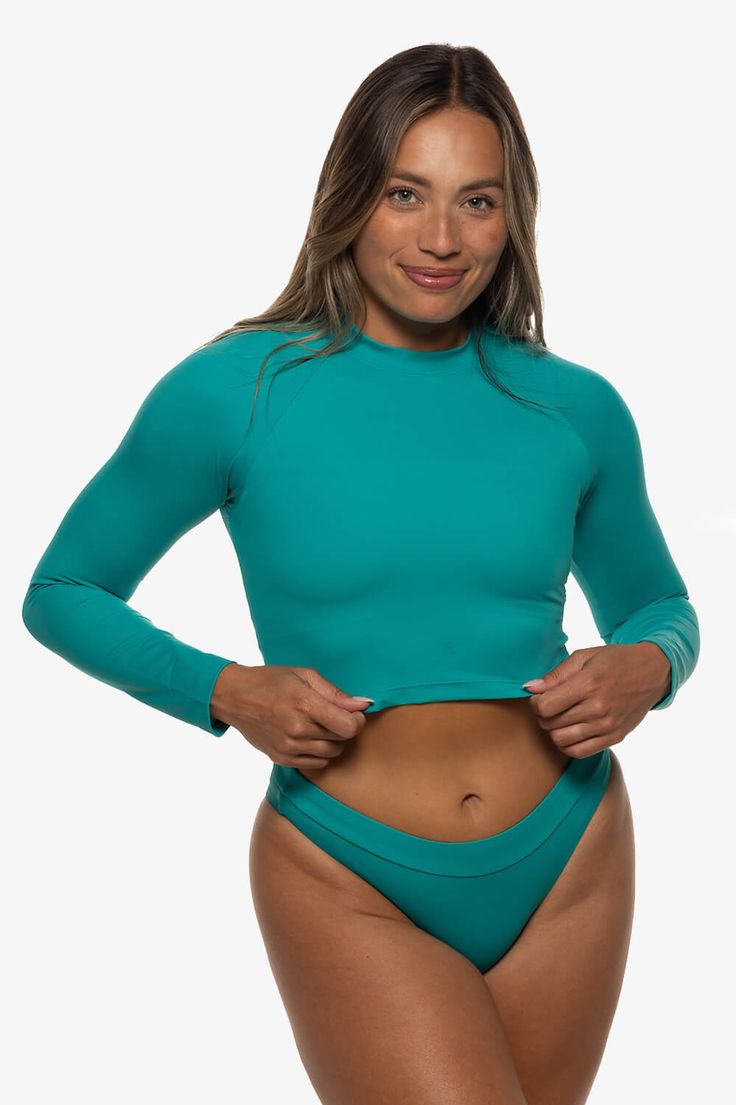 Moana Long Sleeved Crop Rashie | Eryn Krouse x JOLYN Stretch Solid Color Rash Guard For Beach, Blue Stretch Rash Guard For Water Sports, Stretch Rash Guard With Thumbholes For Water Sports, Green Uv Protection Beachwear Rash Guard, Green Beachwear Rash Guard For Surfing, Green Stretch Rash Guard For Beach, Green Fitted Rash Guard For Surfing, Fitted Green Rash Guard For Surfing, Green Rash Guard For Surfing Beachwear