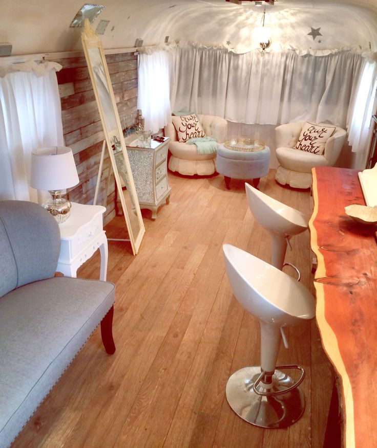 a living room filled with furniture next to a wooden table and white chairs on top of a hard wood floor