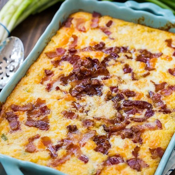 a casserole with bacon and cheese in a blue dish on a wooden table