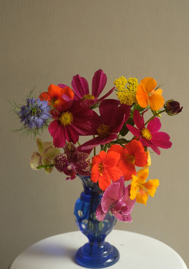 a blue vase filled with colorful flowers on top of a white table