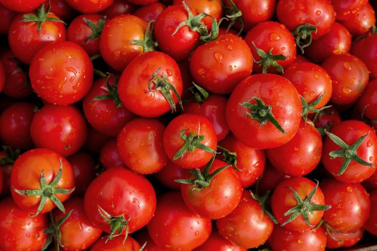 a pile of red tomatoes sitting on top of each other