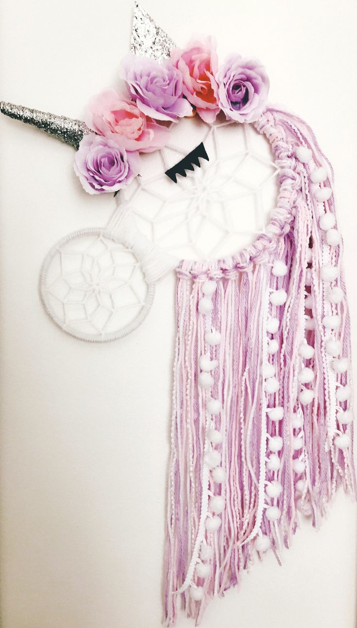 a unicorn dream catcher with flowers on it's head is hanging from the wall