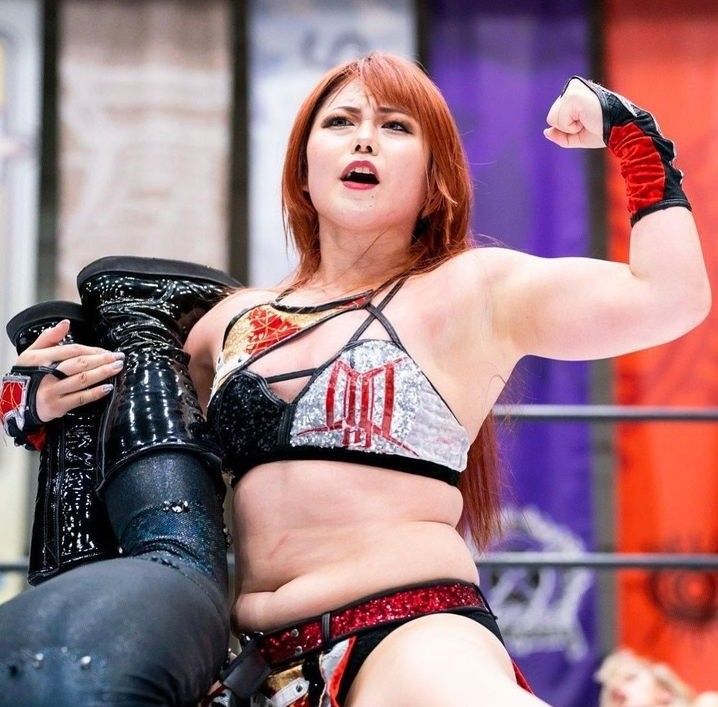 the woman is posing with her arm in the air while holding a wrestling glove and looking at the camera