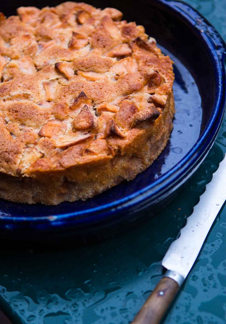 a cake sitting on top of a blue plate next to a knife and spoons