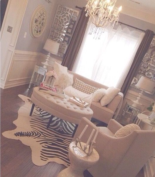 a living room filled with furniture and a chandelier hanging from the ceiling in front of a window