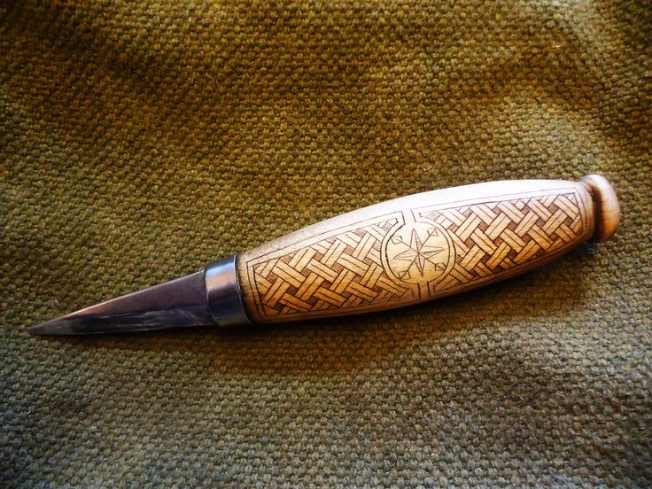 a knife that is sitting on top of a cloth with a pattern on the blade