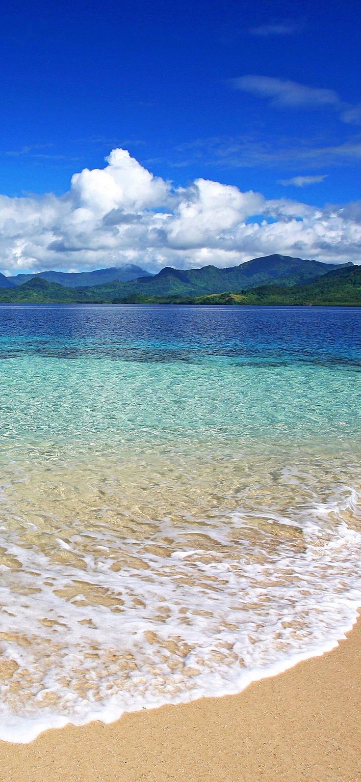 the ocean is clear and blue with white clouds