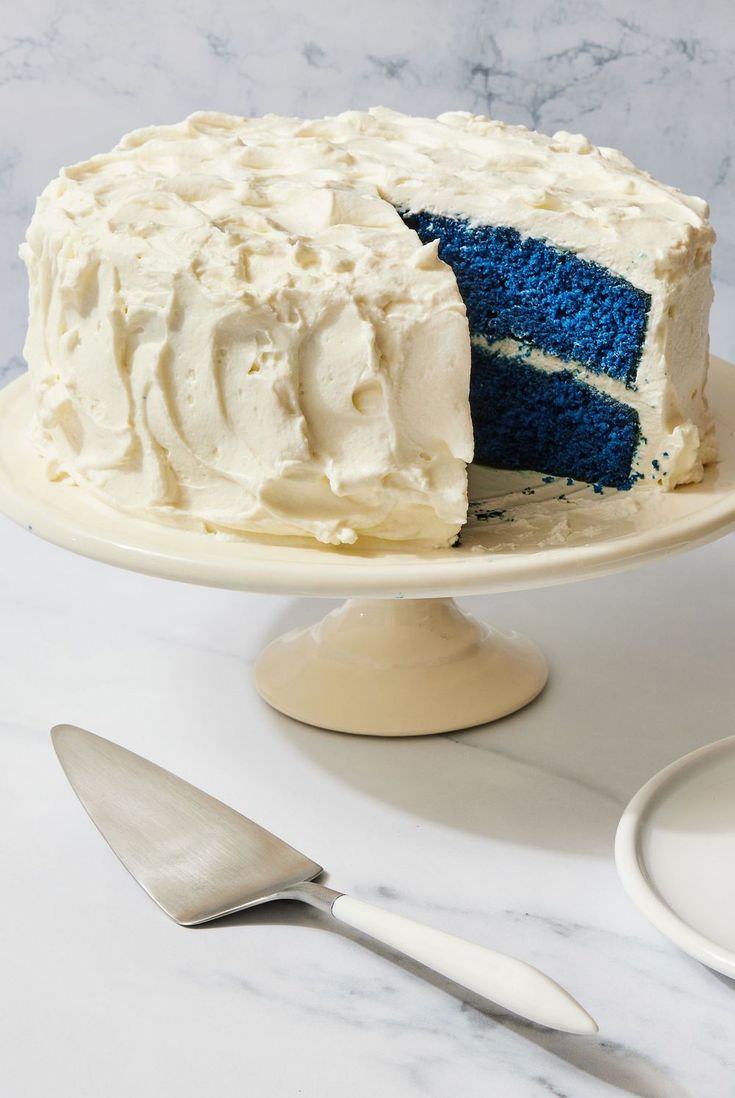 a cake with white frosting and blue icing sitting on a plate next to a fork