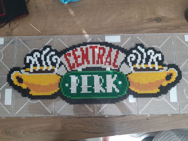 a cross stitch rug with coffee cups and the words, central perk on it