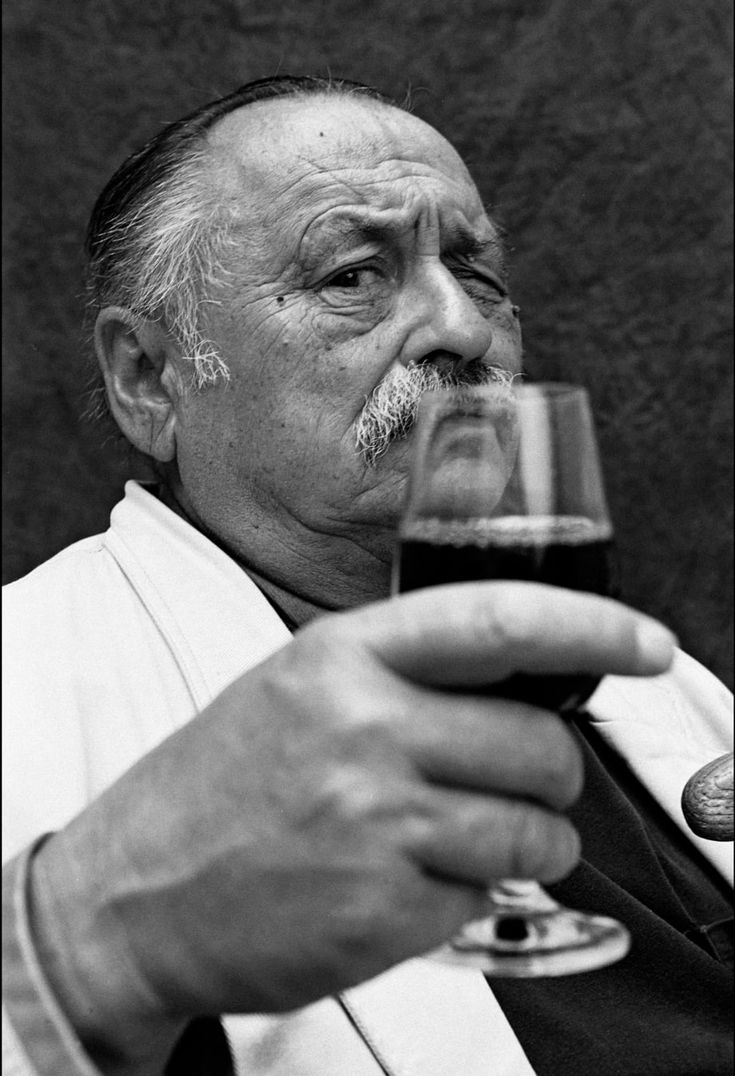 an old man holding a glass of wine