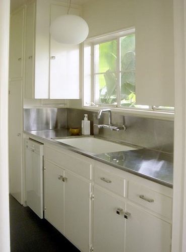 an empty kitchen with white cabinets and stainless steel sink in the corner, looking out to the outside