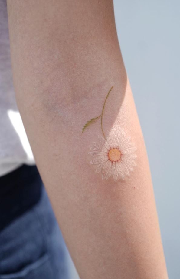 a woman's arm with a small flower tattoo on the left side of her arm