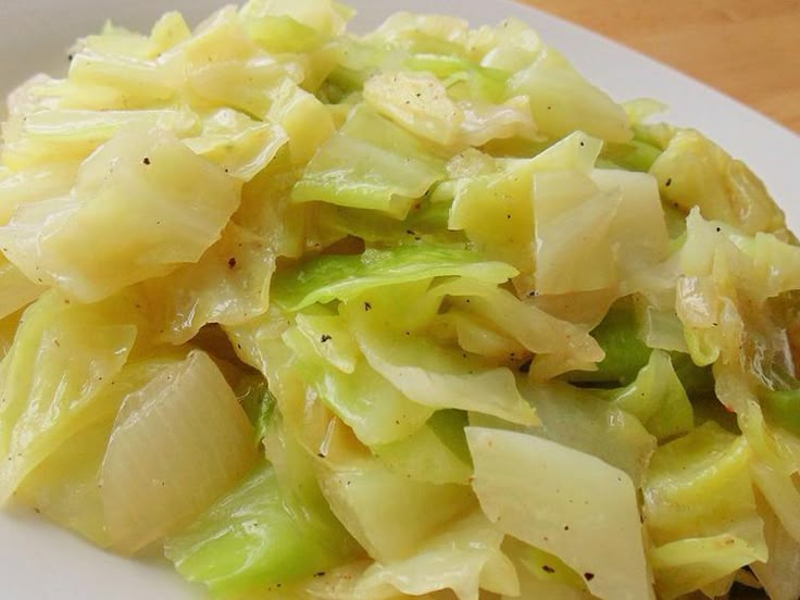 a close up of a plate of food with cabbage and onions on it, next to a fork