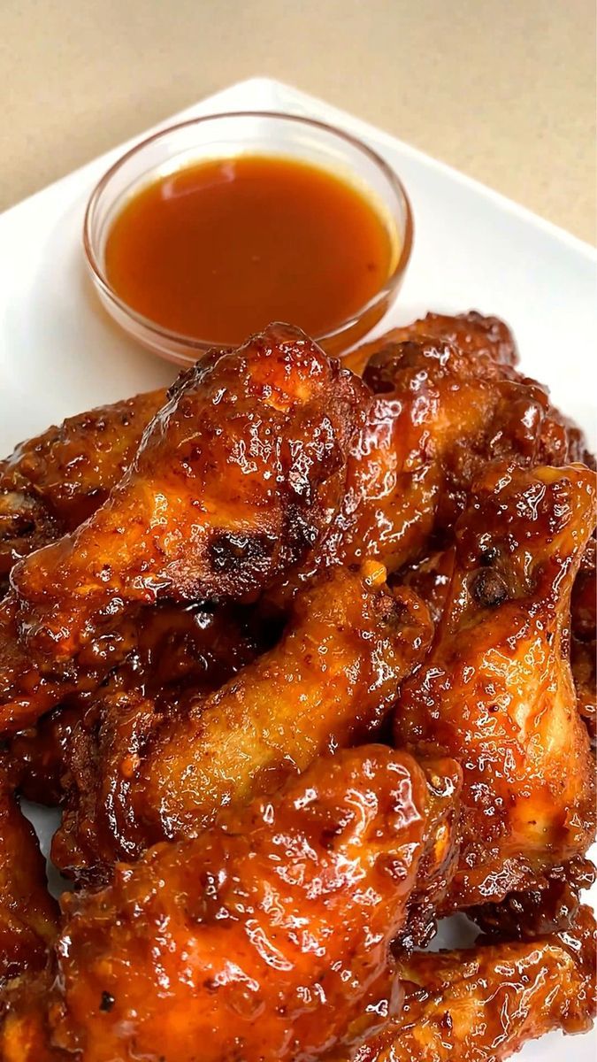 some chicken wings on a white plate with sauce