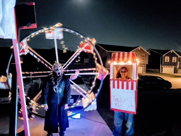 a man holding a sign next to a ferris wheel