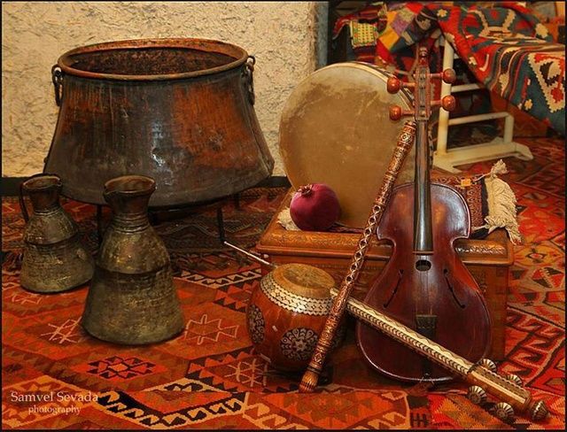 an assortment of musical instruments sitting on top of a rug next to two vases