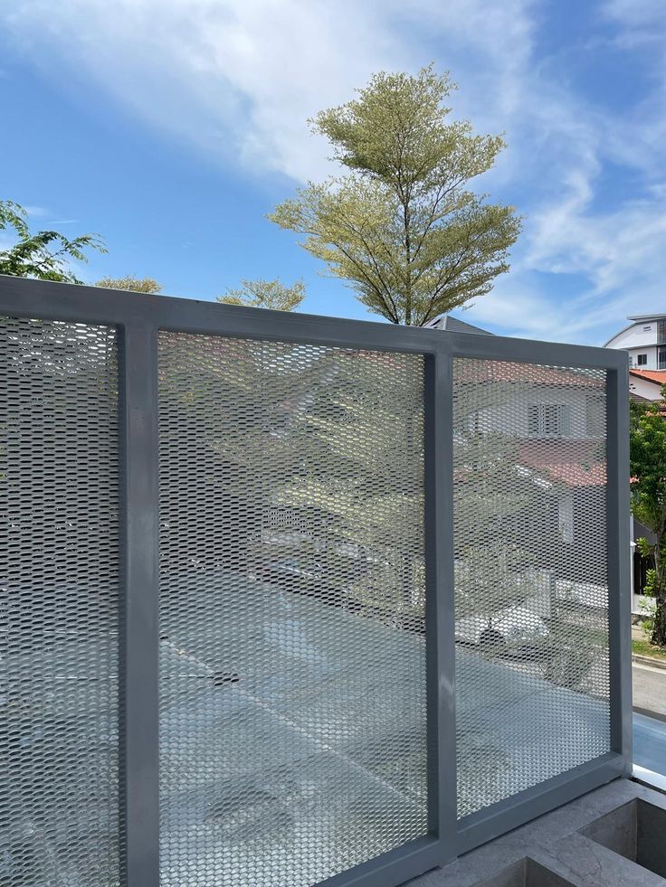 a fenced in area next to a building with trees on the side and blue sky above