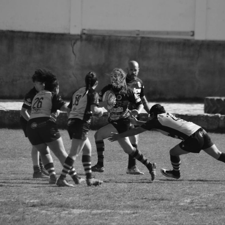 a group of young people playing a game of frisbee on a field in black and white