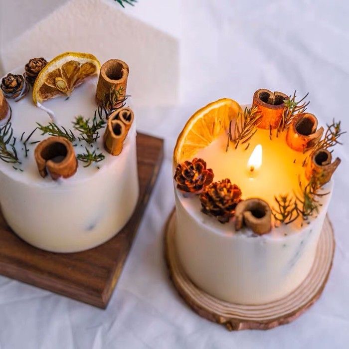 two cakes decorated with orange slices and pine cones are sitting on a wooden tray next to each other