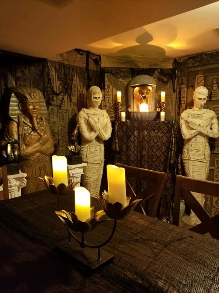 candles are lit on the table in front of two statues with heads and hands behind them