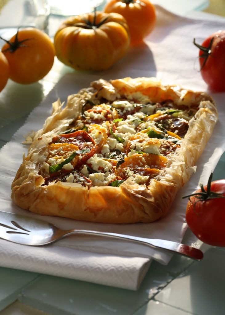 a pizza sitting on top of a white napkin next to tomatoes and other vegetables in the background