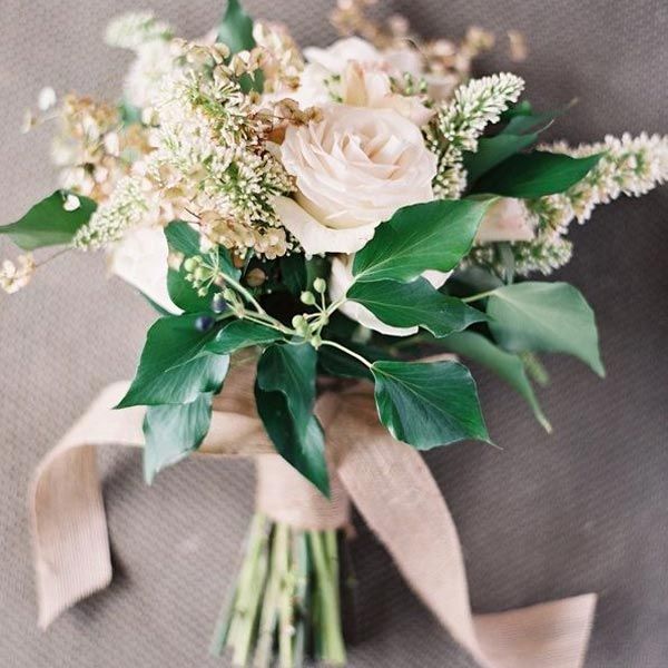 a bridal bouquet with white flowers and greenery on the bottom, tied in brown ribbon