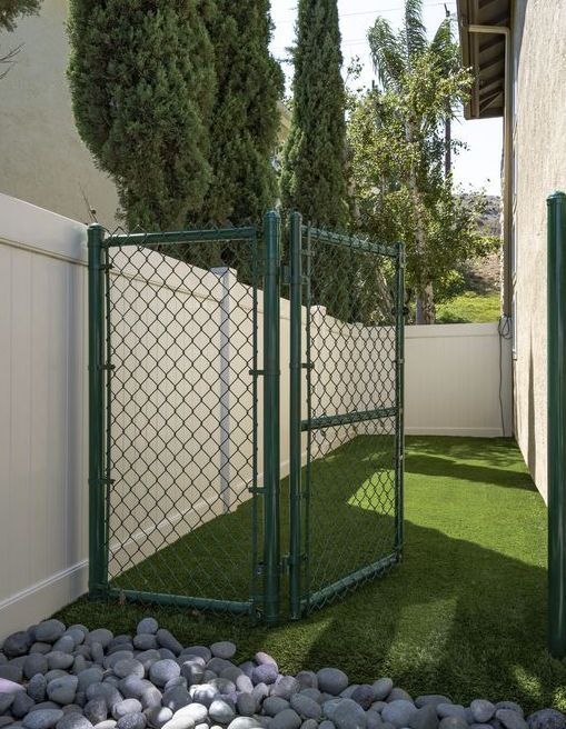 a fenced in area with rocks and grass