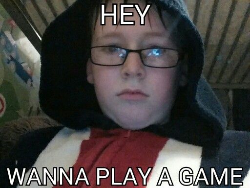 a young boy wearing glasses and a hoodie with the caption hey wanna play a game