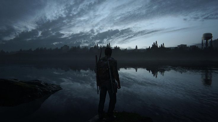 a man standing in front of a body of water at night with the sky covered in clouds