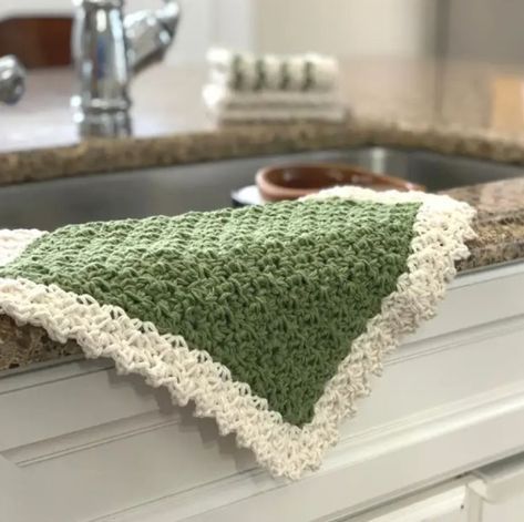 a green and white crocheted dishcloth on a kitchen sink counter top next to a faucet