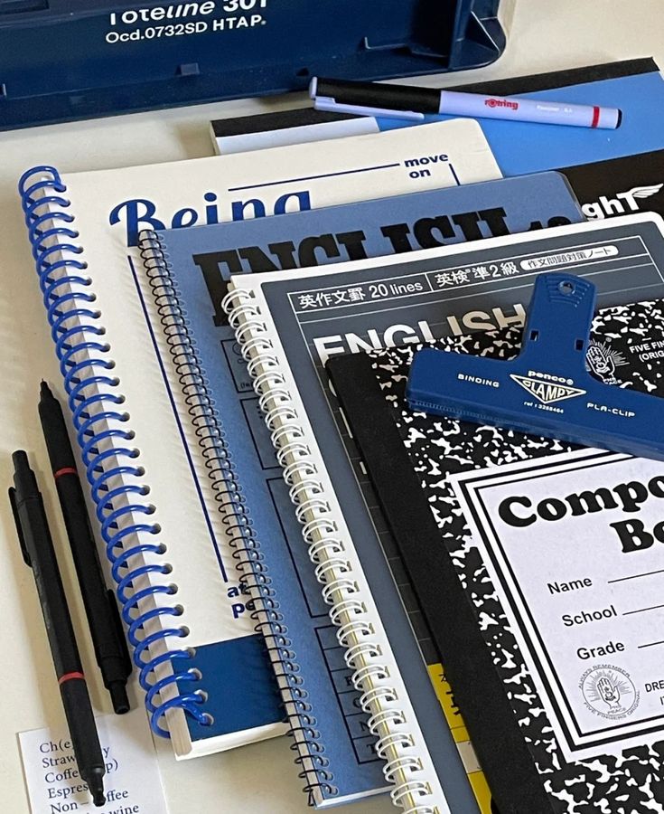 notebooks and pens are sitting on a table next to each other in front of a blue box