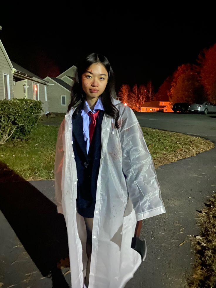 a woman in a raincoat is standing on the sidewalk