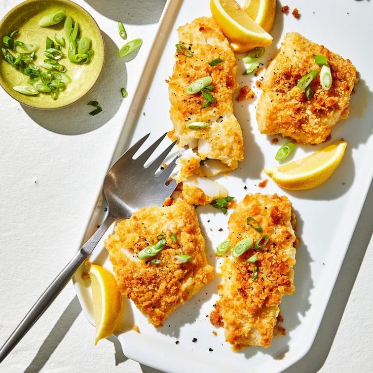 some food is laying on a plate with lemon wedges and a fork next to it