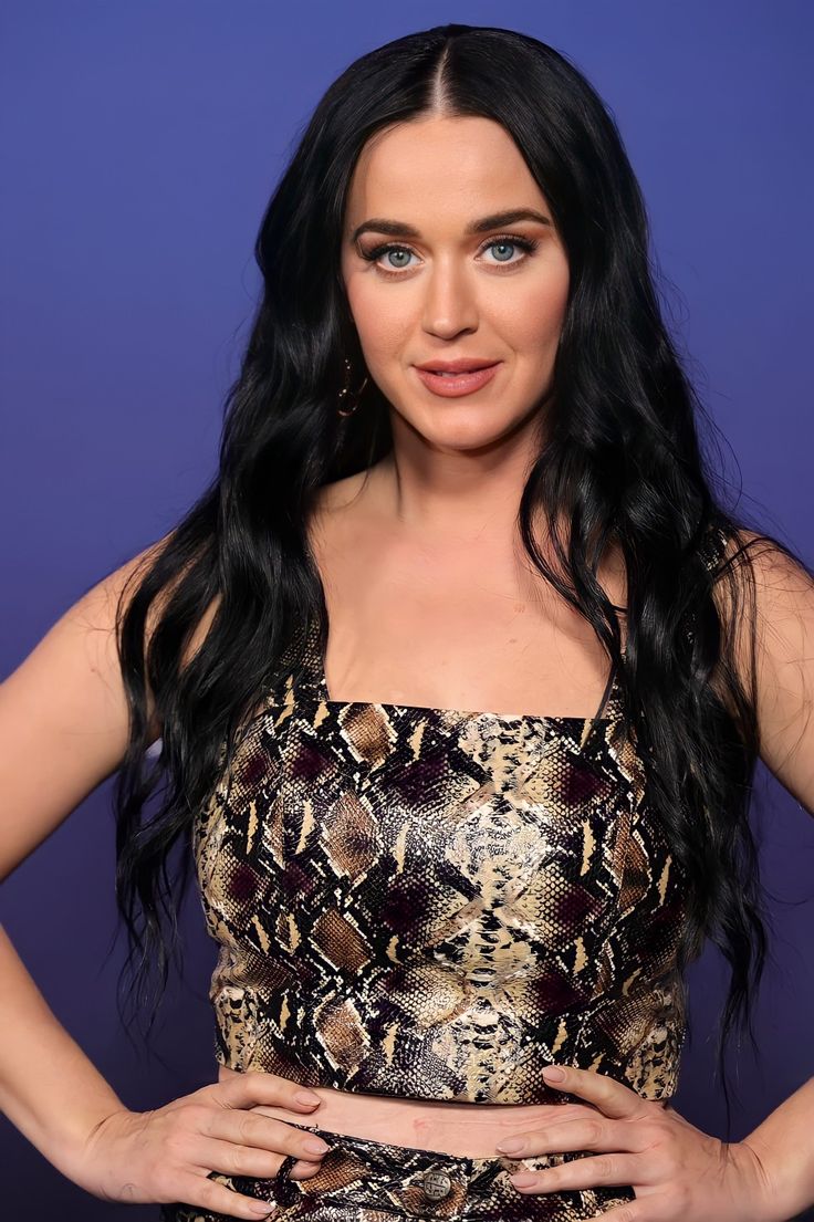 a woman with long black hair wearing a snake skin top and matching pants is posing for the camera