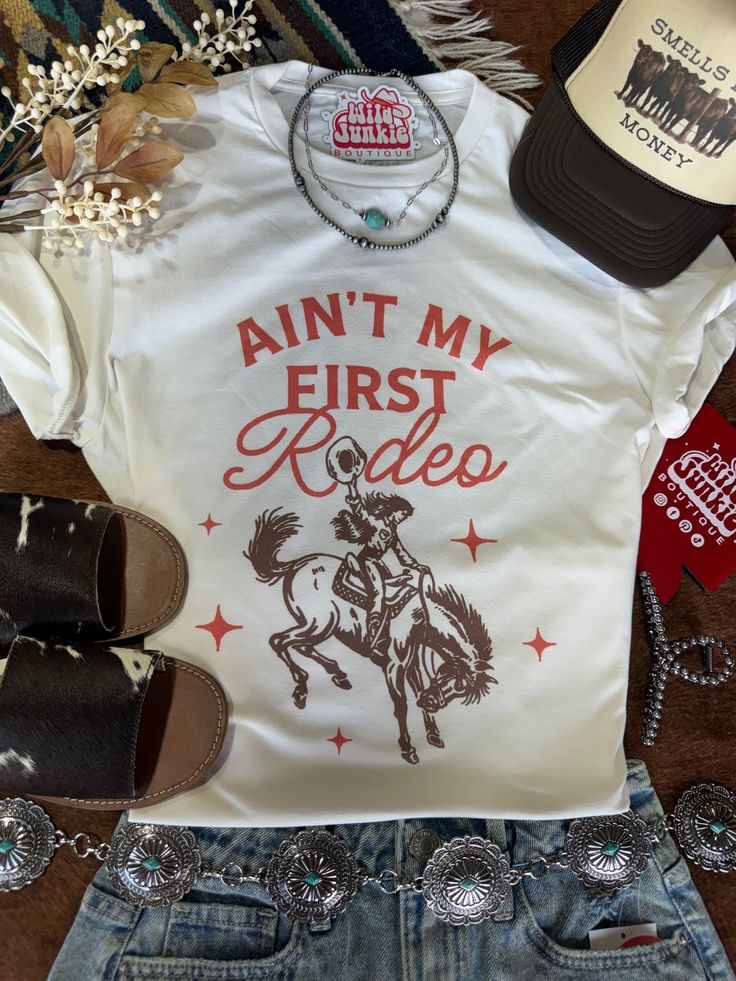 Show off your cowgirl confidence with the Ain't My First Rodeo Cowgirl Graphic Tee. Featuring a bold and sassy design, this tee is perfect for seasoned cowgirls who know their way around the ranch. Soft and comfortable, it's great for casual days, rodeo events, or just adding a touch of country flair to your everyday look. Saddle up and flaunt your rodeo spirit with this fun tee! Unisex fit Made in the USA Not My First Rodeo, Cowgirl Graphic, Rodeo Events, My First Rodeo, Rodeo Cowgirl, First Rodeo, Plus Size Shopping, The Ranch, Trinidad And Tobago