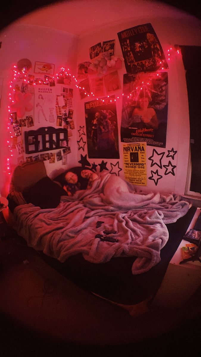 a bedroom with pink lights and posters on the wall above it is shown in a fisheye lens