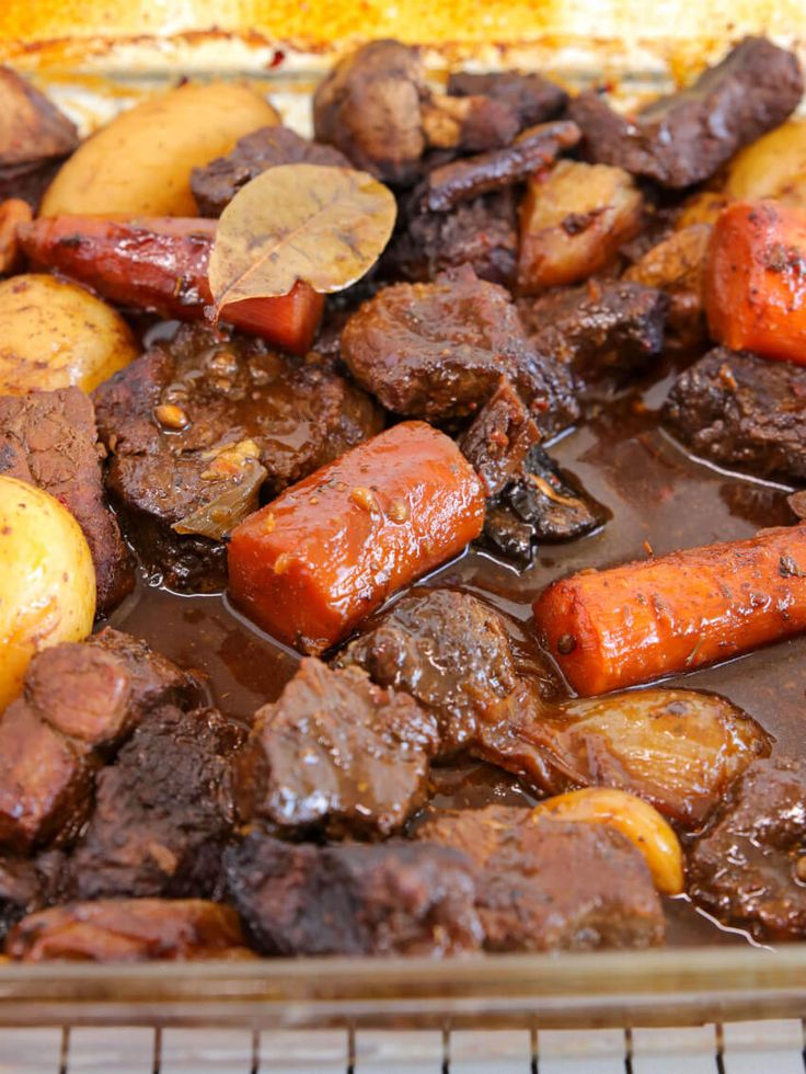 meat, potatoes and carrots are being cooked in the oven