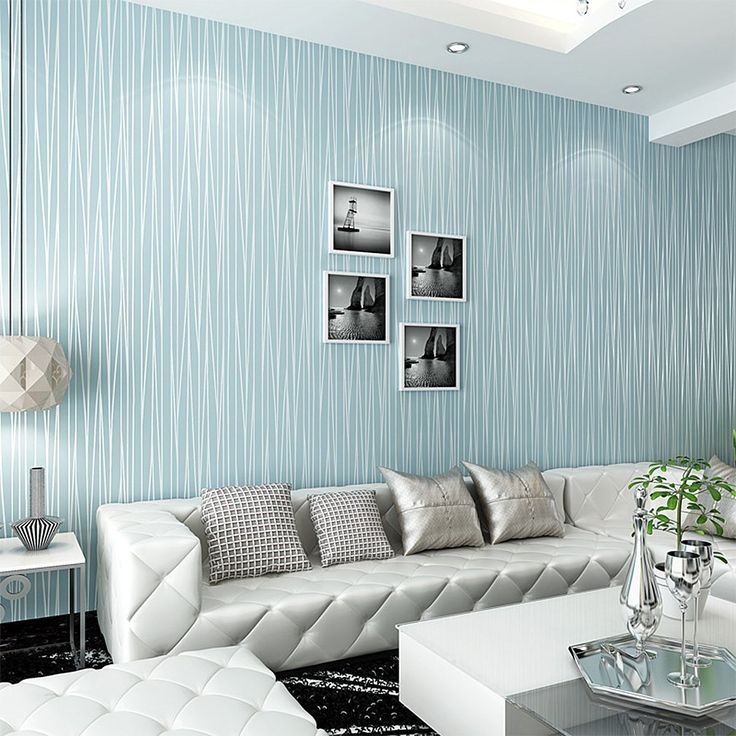 a living room with blue wallpaper and white couches in it's center