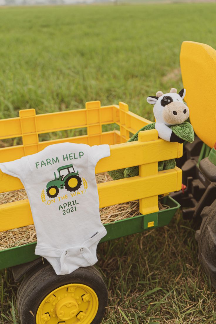 a toy tractor with a baby's farm help shirt on the front and an infant's t - shirt on the back