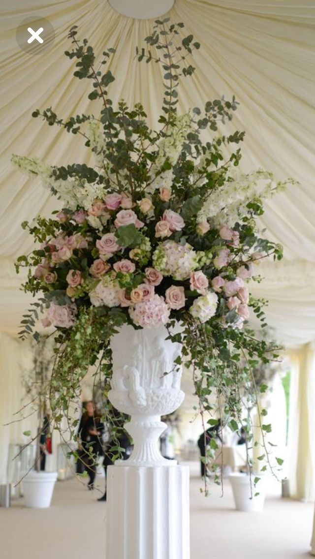 a white vase filled with lots of flowers on top of a table in a tent