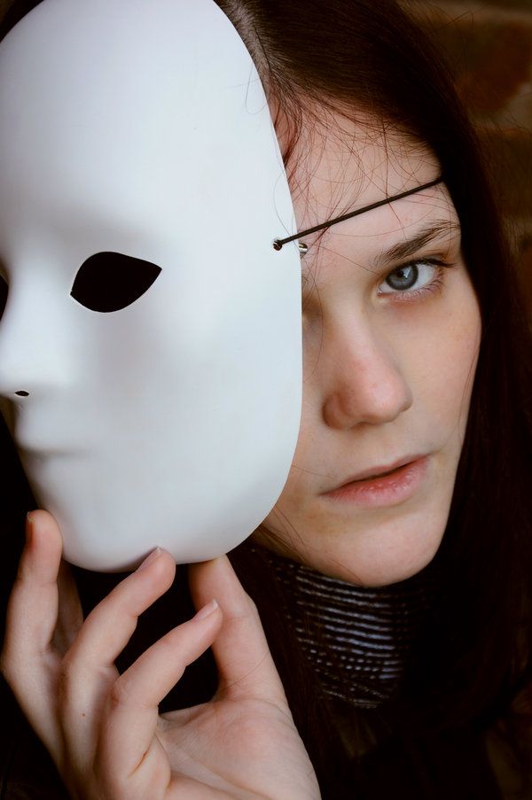 a woman holding up a white mask to her face