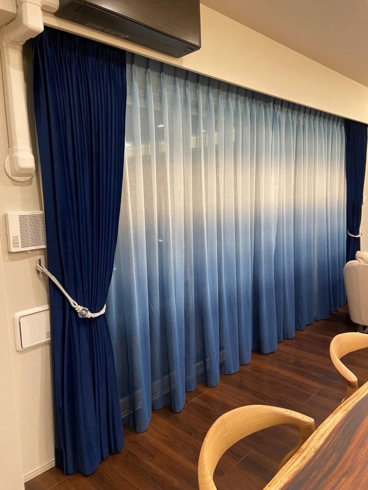 a living room with blue curtains and wooden floors