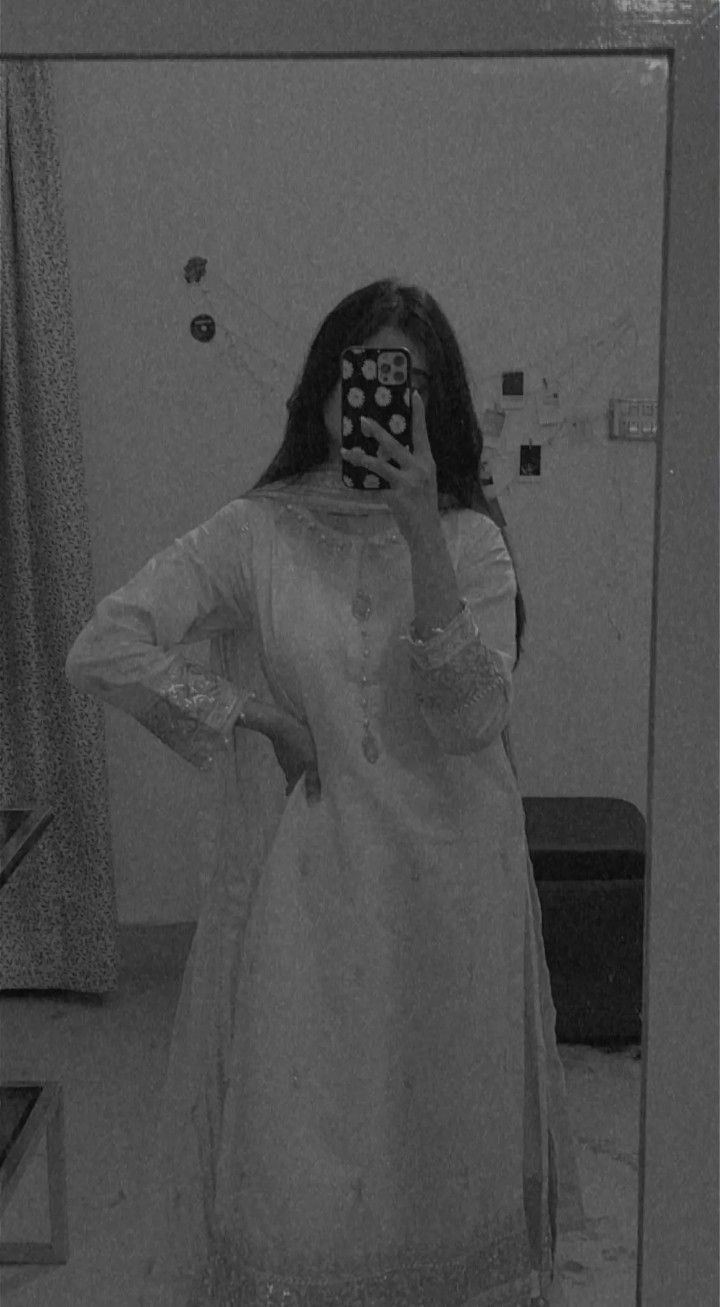 a woman taking a selfie in front of a mirror while wearing a white dress