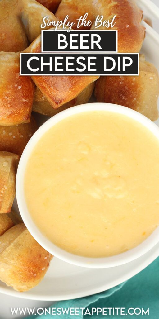 beer cheese dip in a white bowl on a plate with bread rolls and dipping sauce